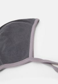Soutien-gorge gris à texture lisse, avec une bordure lavande. Forme triangulaire avec des bretelles réglables et des détails de couture le long des bords.