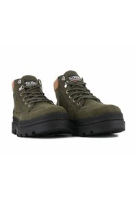 Botas de senderismo de color verde oscuro, hechas de ante y goma, con ojales de metal, diseño de cordones y una gruesa suela de goma negra con tacos.