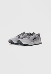 Baskets de trail grises avec dessus texturé, bout renforcé et semelle extérieure Vibram noire. Comprend des lacets gris et un design léger.