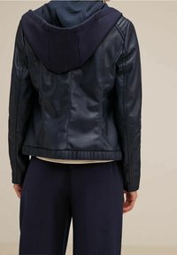 Marinblå läderjacka med en kontrasterande mörkblå huva. Har ribbade ärmslut och midja, figursydd form och slät textur. Enkelt design.