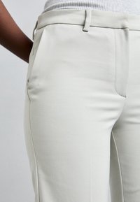 Lichtgrijze op maat gemaakte broek met een gladde textuur, voorzien van zijzakken en een slank ontwerp. De stof lijkt lichtgewicht en aansluitend.