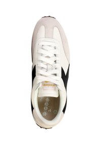 Hvide sneakers med sorte detaljer, lavet af ruskind og læder, rund tå, flade hvide snørebånd og et gult mærke på tungen. Tekstureret sål.