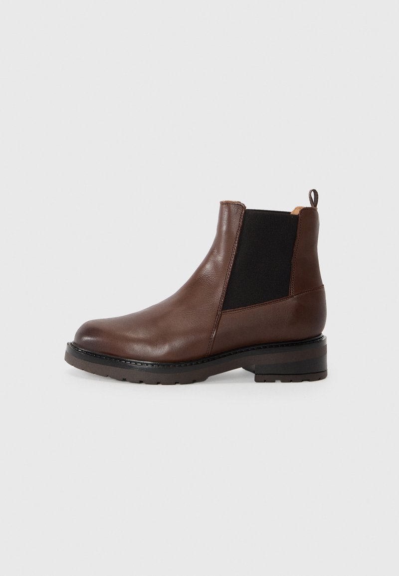 Botte cheville en cuir brun avec des panneaux élastiques sur les côtés, une pointe arrondie et un petit talon empilé. Texture lisse avec une semelle en caoutchouc durable.