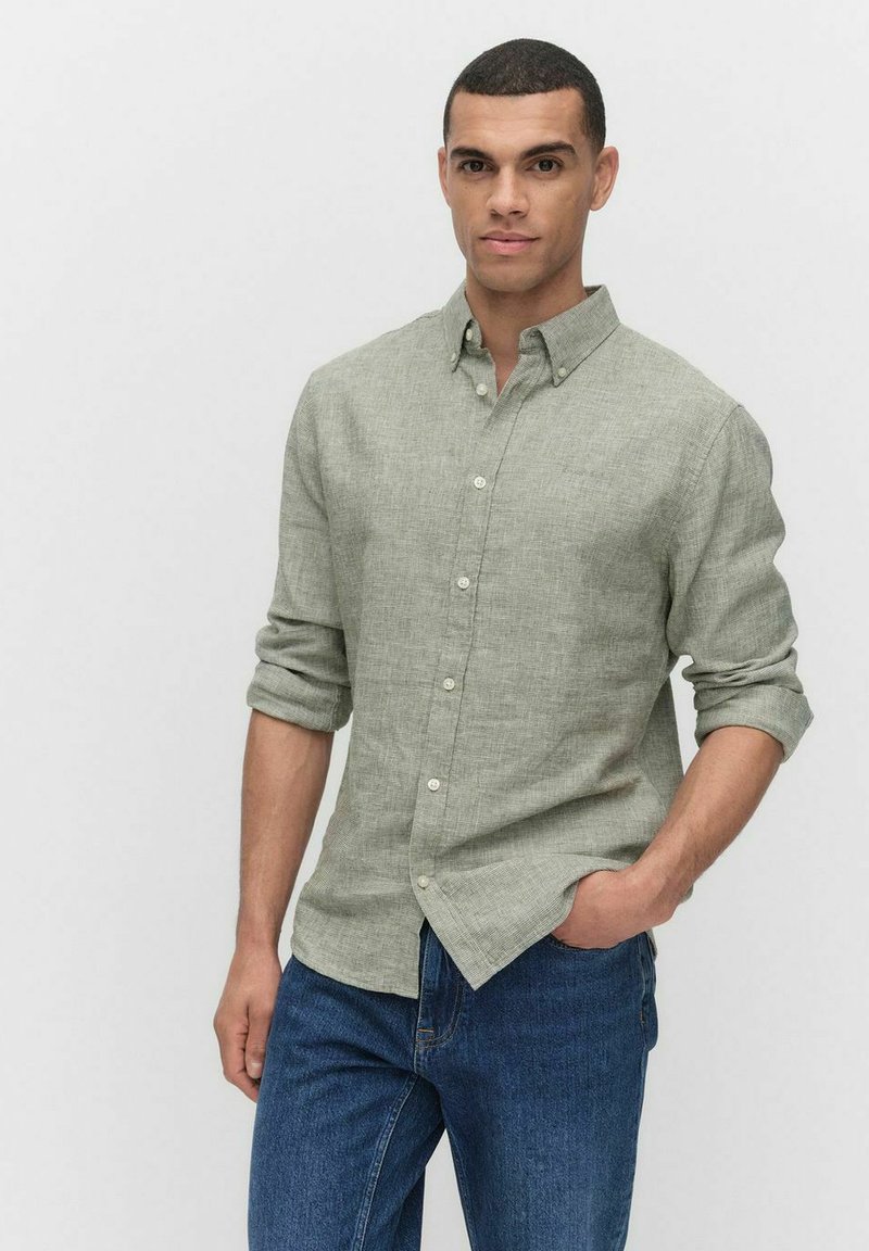 Lichtgroen overhemd met knopen in een gestructureerde stof, met een kraag en opgerolde mouwen, gecombineerd met blauwe spijkerbroeken.
