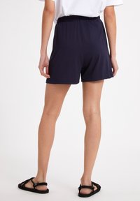 Shorts bleu marine à taille élastique avec une coupe ample, fabriqués en tissu doux. Caractérisés par un design simple sans accents ni motifs supplémentaires.