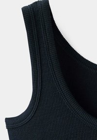 Gros plan d'un débardeur en tissu côtelé noir montrant la bretelle d'épaule et les détails de couture de l'encolure arrondie.