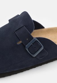 Námořnické semišové slip-on boty s širokým popruhem a nastavitelnou přezkou, s korkovou stélkou a texturovanou černou gumovou podrážkou.