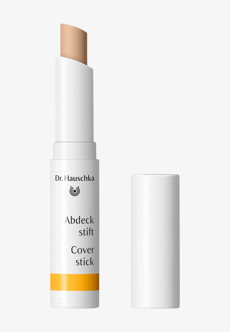 Dr. Hauschka Cover stick with a creamy beige tip, housed in a white cylindrical case with a yellow accent and black brand text.