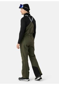 Olijf groene skibroeken met verstelbare banden, ritszakken aan de zijkanten en zwarte accenten op de onderkant van de broek. Draag ze over een aansluitend zwart thermoshirt.