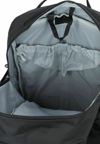 Interior de mochila negra con forro gris, que cuenta con cierre de cremallera, bolsillo elástico y cinta de webb para la organización.