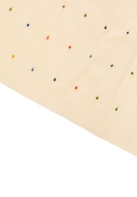 Tessuto color crema con piccoli puntini ricamati di diversi colori, distribuiti uniformemente e disposti in linee diagonali.