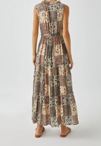 Maxikjole med patchworkdesign, der kombinerer blomster- og dyreprint. Har en samlet talje og lagdelte lag i afdæmpede farver.