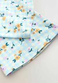 Tessuto di cotone floreale color azzurro chiaro con motivo a quadretti. Presenta fiori gialli e rosa, steli verdi e una texture morbida.