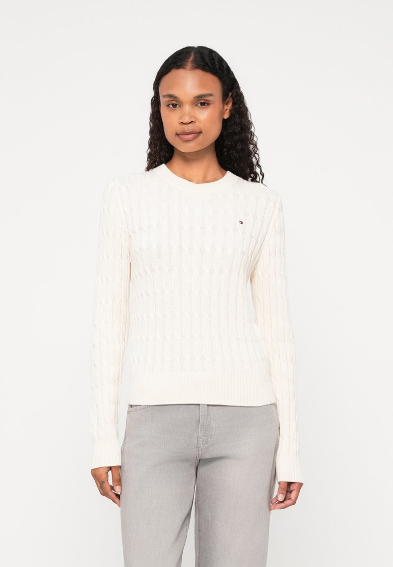 Kremowy sweter w splot warkoczowy z okrągłym dekoltem, prążkowanym dołem i długimi rękawami; posiada małe logo na piersi.