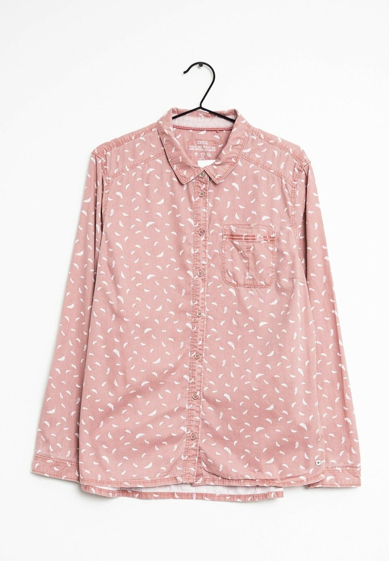 Chemise rose à manches longues avec motifs de feuilles blanches, poche poitrine et col pointu, accrochée sur un cintre noir sur fond blanc.