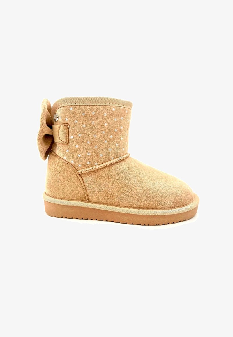 Botín de ante marrón claro con punta redonda, adornado con patrones de estrellas plateadas y un gran lazo lateral. Presenta una suela de goma plana.