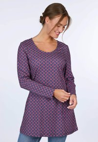 Langärmlige Tunika aus dunkelblauem Stoff mit einem sich wiederholenden roten und rosa Muster, mit einem Rundhalsausschnitt und leicht ausgestellt Silhouette.