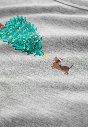 Grijze stof met een afbeelding van een groene kerstboom versierd met kleurrijke ornamenten en een bruine hond met een kerstmanhoed, die naar een ster reikt.