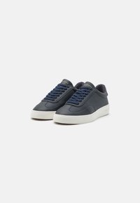 Adidași din piele bleumarin cu talpă din cauciuc alb, vârf rotund și șireturi texturate. Au un design minimalist și un branding subtil pe limba adidașilor.