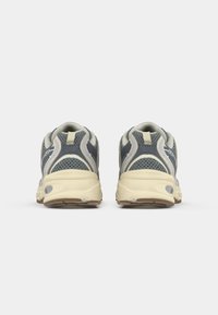 Gray and beige athletic shoes with mesh upper, round toe, cushioned sole, and textured rubber outsole, featuring a logo on the heel.