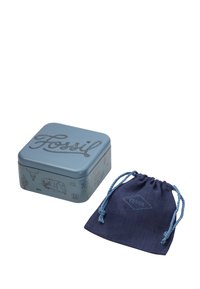 Scatola di latta blu con "Fossil" impresso sulla parte superiore, con illustrazioni sui lati, e un piccolo sacchetto con coulisse blu scuro con il logo "Fossil".