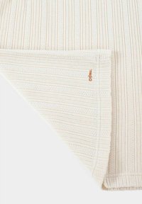 Gestrickte Decke mit cremefarbenen und hellbeigen Streifen. Strukturiertes Muster mit subtilen Akzenten. Hat ein dekoratives Nähdetail in einer Ecke.