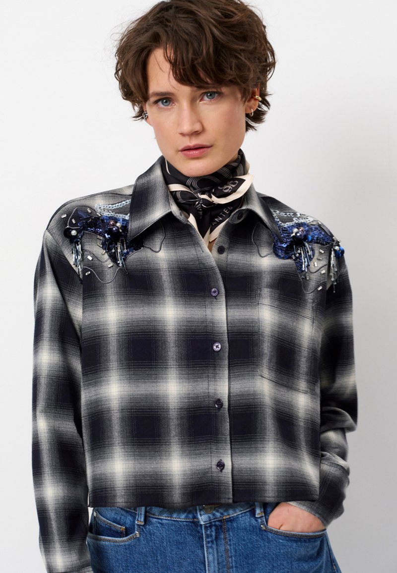 Geknipte geruite overhemd in zwart en grijs met blauwe versieringen op de schouders, knoopsluiting en lichte textuur. Draag met een sjaal.