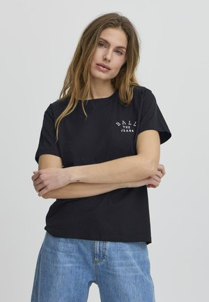 Must nagu puuvillane T-särk lühikeste varrukatega, millel on vasakul rinnaalal valge tekst "BALL THE JEANS". Seljas on helesinised teksapüksid.