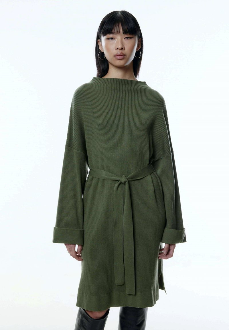 Langärmliges, olivgrünes Strickkleid mit einem lockeren Schnitt, weiten Bündchen und einem Bindegürtel in der Taille. Strukturierter Rippenmuster über das gesamte Kleid.
