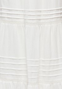 Tissu blanc avec plis pintucks horizontaux et deux bandes de dentelle décorative, montrant une texture froncée et des plis souples.