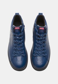 Niebieskie skórzane sneakersy typu high-top z zaokrąglonym noskiem, teksturowanymi akcentami, kropkowanymi sznurówkami i zapięciem na zamek błyskawiczny. Logo Camper umieszczone na języku.