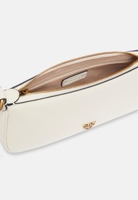 Borsa a spalla in pelle bianca con una texture liscia, cerniera dorata e un'emblema decorativo dorato sulla parte anteriore. L'interno è foderato in beige e presenta tasche.