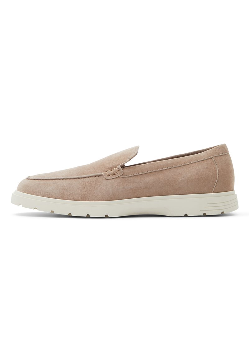 Mocasines de ante beige con punta redondeada, detalles de costura sutil y suela de goma blanca, con un tacón bajo y diseño de fácil poner.