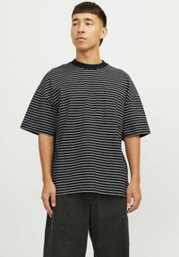 Sort og hvid stribet t-shirt med kort ærme, afslappet pasform og rund halsudskæring, med en lille lomme på venstre side.