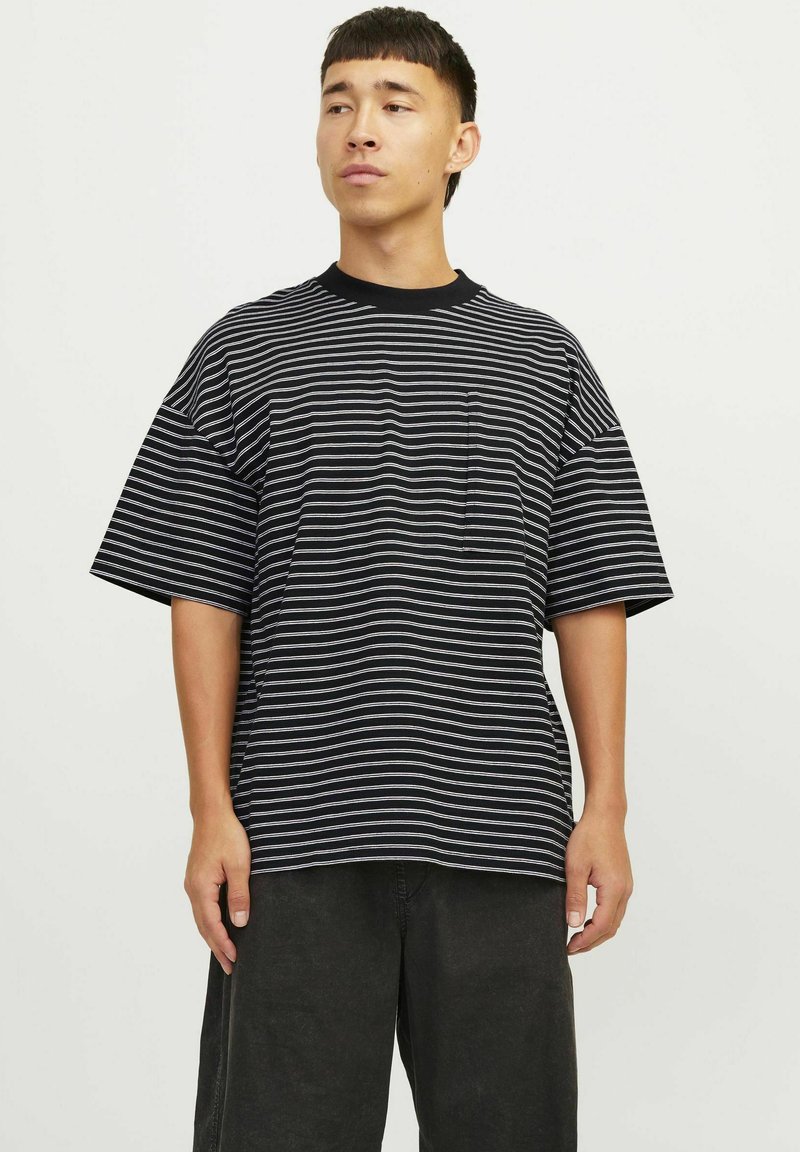Sort og hvid stribet t-shirt med kort ærme, afslappet pasform og rund halsudskæring, med en lille lomme på venstre side.