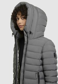 Puffy gray jacket with a large, structured hood. Features horizontal stitching, zippered pockets, and a shiny interior lining.