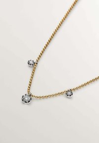 Collar de cadena de bolas doradas con tres engastes en tono plateado y piedras transparentes, que exhibe un diseño sencillo pero elegante.