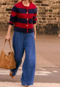 Cárdigan a rayas rojas y marino con botones dorados, combinado con jeans de mezclilla azul de pierna ancha y un bolso tote marrón.