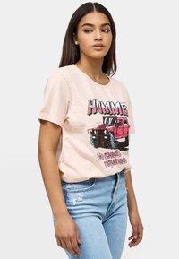 Lichtroze t-shirt met korte mouwen met een graphic van een rode Hummer en de tekst "Geen wegen nodig." Zacht materiaal en een ontspannen pasvorm.