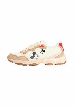 Zapatilla beige y blanca con suela gruesa, diseño con cordones, dos caras de Mickey Mouse en el lateral y detalle rojo en el talón.