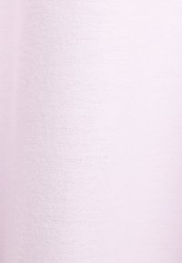 Tissu uni rose clair avec une texture tricotée visible uniformément répartie sur toute la surface.