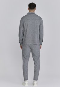 Set de îmbrăcăminte de leisure gri, cu model, compus din cămașă cu guler și pantaloni ajustați. Textură moale, croială lejeră, asortat cu încălțăminte albă.