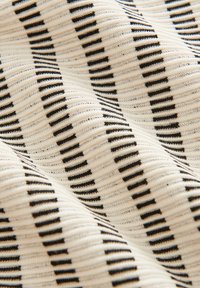 Knitted fabric featuring a wavy pattern of alternating black and cream stripes, with a soft texture and visible ribbing detail throughout.