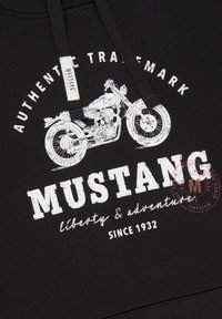 Sudadera negra con un gran gráfico blanco de una motocicleta y texto: "MUSTANG", "libertad y aventura" y "desde 1932". Tejido suave.