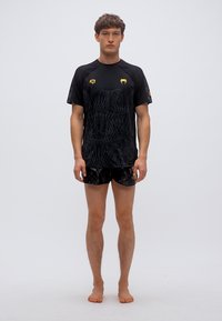 Μαύρο αθλητικό T-shirt με κοντά μανίκια και υφή, σετ με μαύρο σορτς. Διαθέτει κίτρινες λεπτομέρειες κοντά στους ώμους.