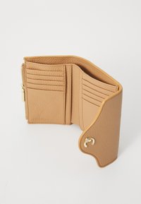 Tan leren portemonnee met meerdere kaartsleuven, een ritscompartiment en een zichtbaar logo. Gestructureerd oppervlak en gebogen randen. Gouden hardware accent.
