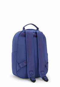 Sac à dos en tissu violet avec bretelles rembourrées, poignée supérieure et poche latérale. Forme arrondie avec texture lisse et coutures surpiquées.