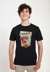 T-shirt nera con una grafica in stile retro di una mucca sorridente con orecchini, circondata da testo e dettagli colorati in blu e oro.