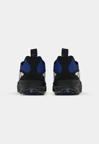 Une paire de baskets Nike Air noires et bleues vue de l'arrière, présentant des semelles épaisses et des languettes de tirage avec des logos Nike Air.