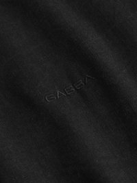 Tessuto nero con una superficie liscia caratterizzato dal logo in rilievo "GABBA". Il tessuto appare uniforme, senza motivi o accenti.